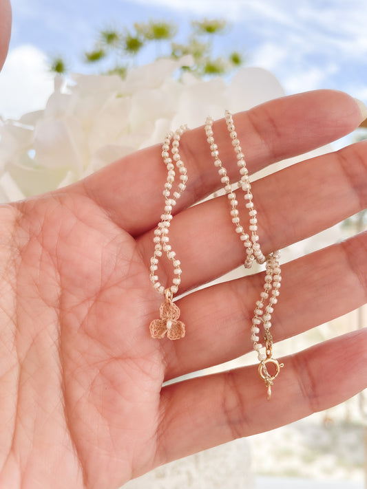 Aiyana ketting Sfeerfoto; gehaakte ketting en bedel, ambacht, vlinder bedel gehaakt donkerbeige, ketting gehaakt van gouddraad en witte Miyuki kraaltjes 