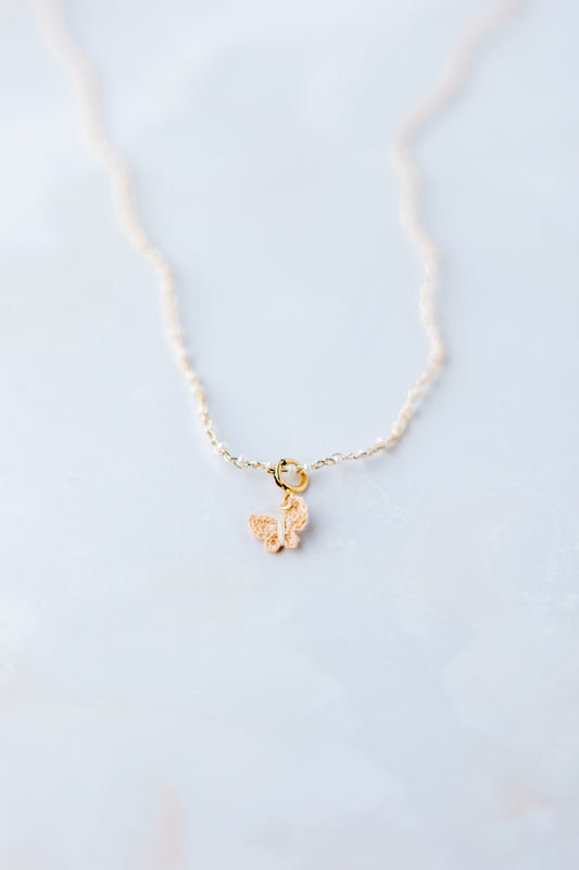 Sfeer foto Yara micro gehaakte vlinder ketting; ambacht, vlinder gehaakt van naaigaren donkerbeige, ketting gehaakt met gouddraad en 1 mm glaskraaltjes